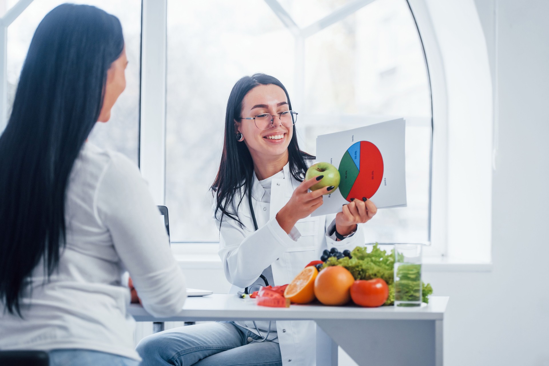 Female nutritionist with graph gives consultation to patient indoors in the office